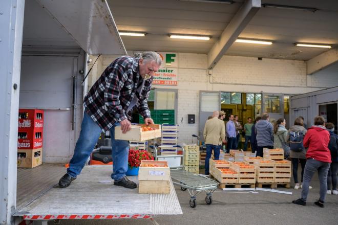 Ein Mann lädt Obstkisten aus seinem Transporter aus