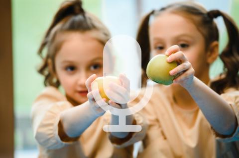 Zwei Mädchen halten Äpfel in die Kamera